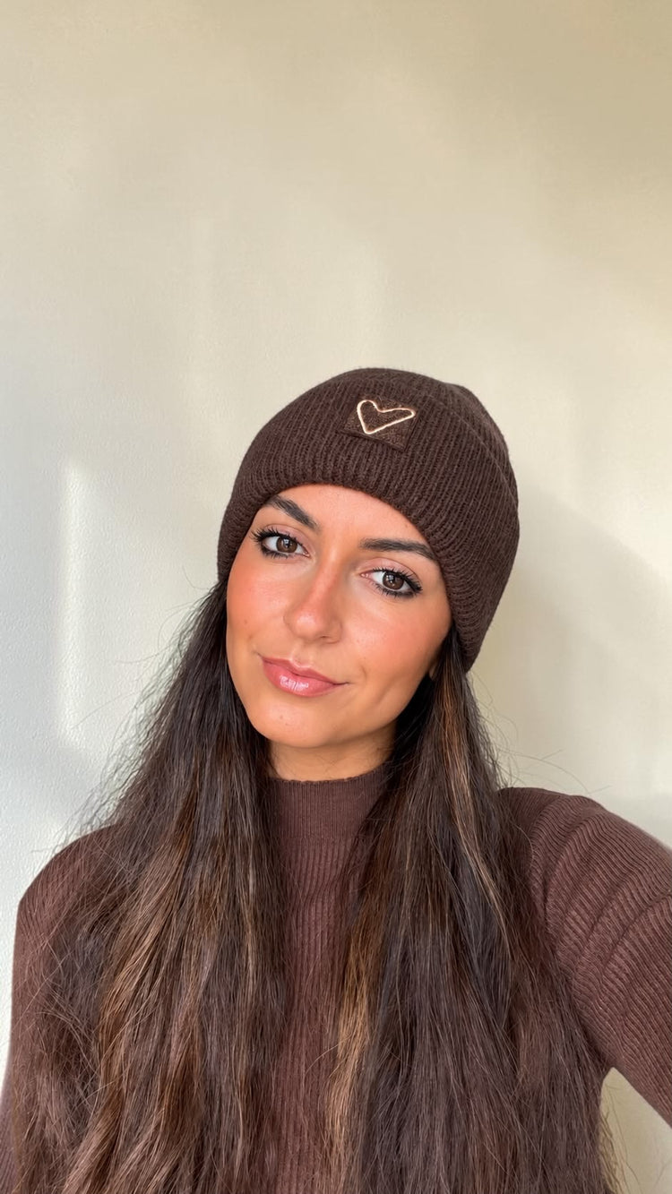 Close-up of the cocoa brown Sherpa Heart Beanie worn over long hair